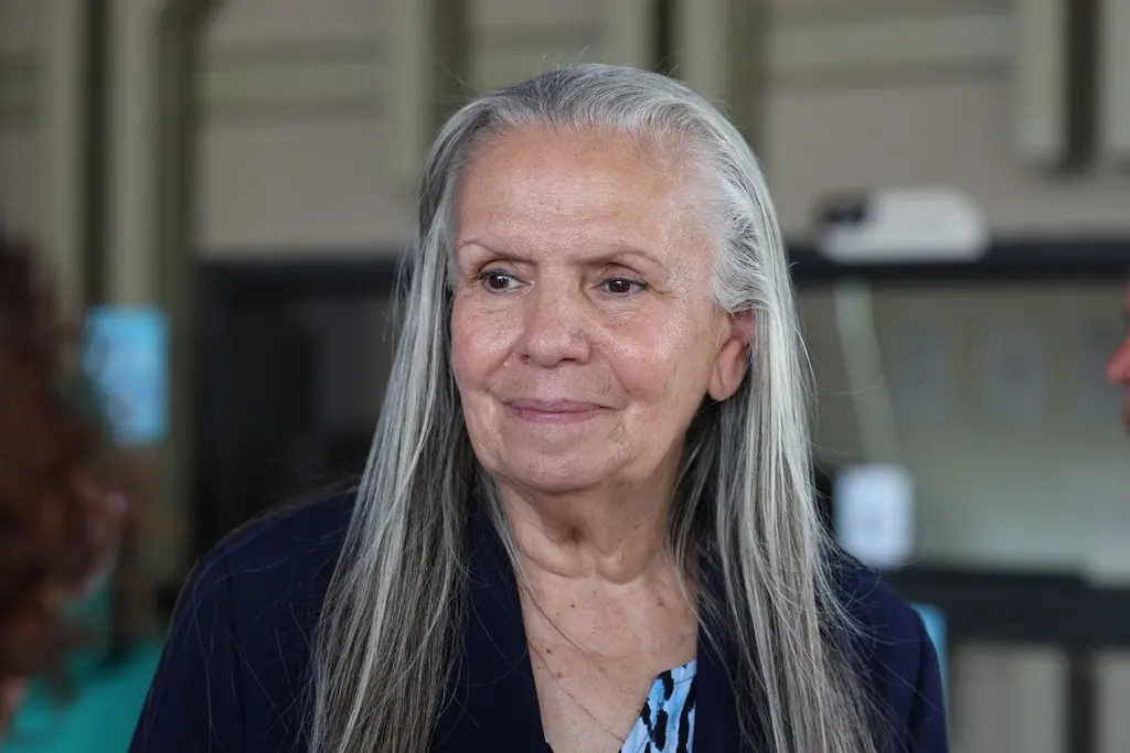 Foto horizontal em plano fechado que mostra a desembargadora Maria Erotides, com semblante alegre. Ela é uma senhora branca, de cabelos longos, lisos e grisalhos, olhos castanhos, usando blazer azul marinho. 