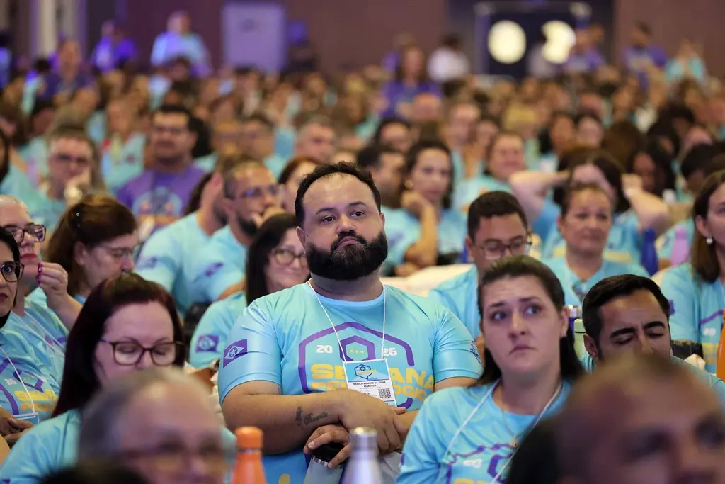 Foto horizontal em plano aberto que mostra centenas de profissionais da Educação estadual sentados, participando da Semana Pedagógica. Todos usam camiseta azul clara com logomarca do evento. 