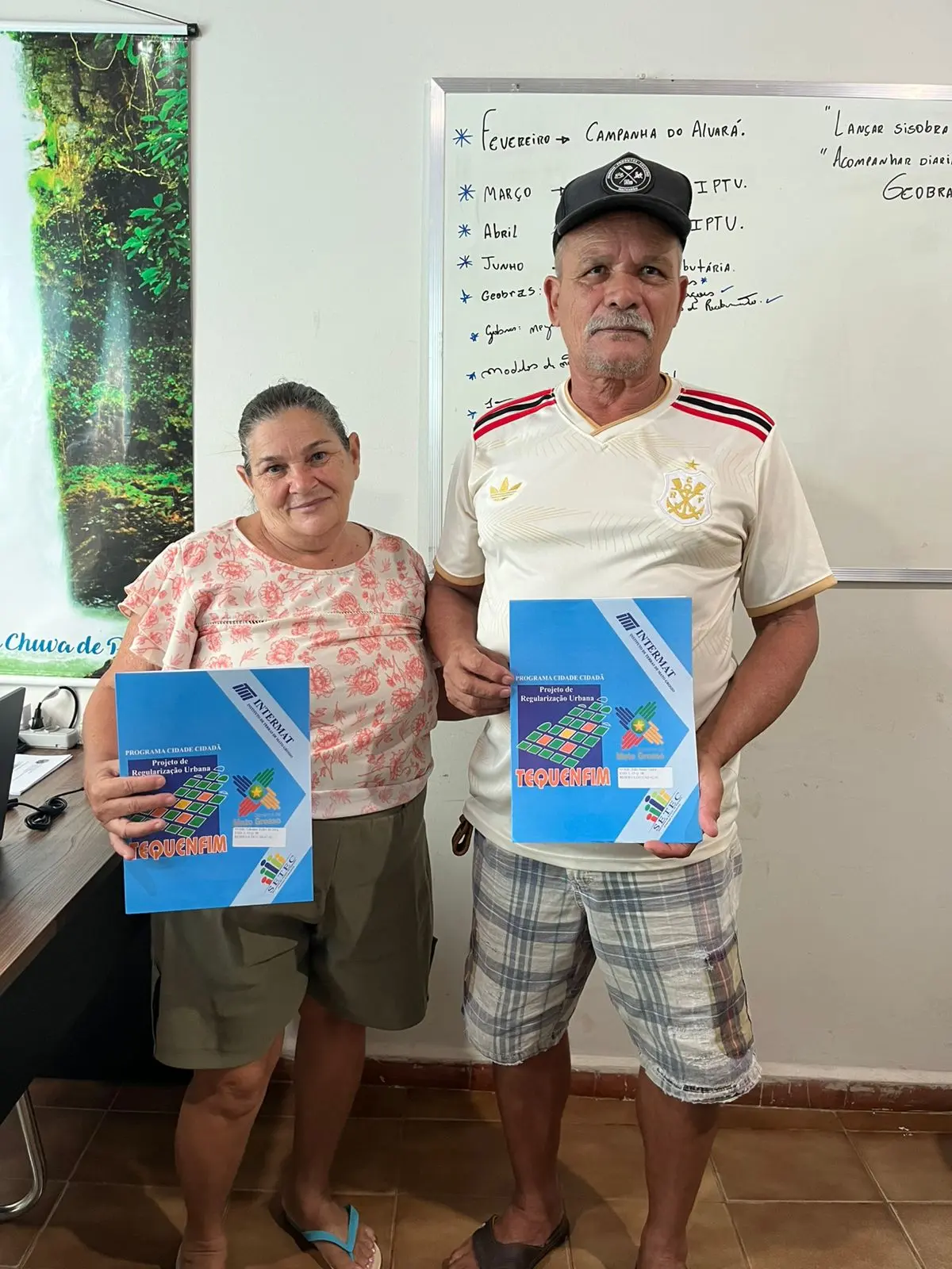 Foto que mostra um homem e uma mulher, moradores de Reserva do Cabaçal, segurando os títulos definitivos de propriedade recebidos.