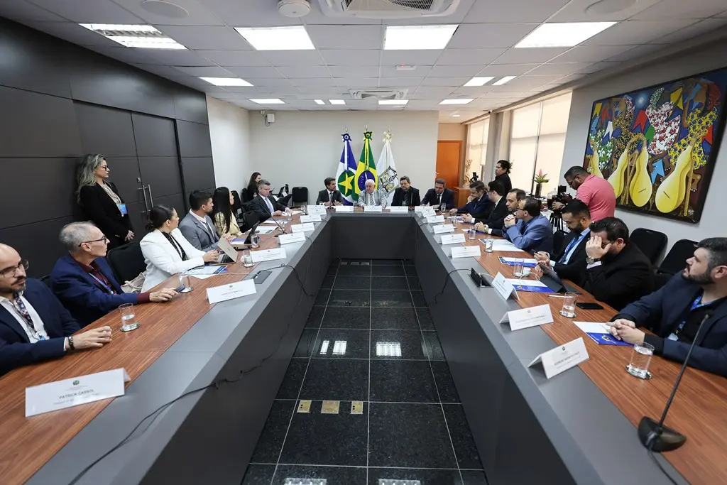 Foto horizontal em plano aberto, que mostra uma sala de reuniões com uma mesa em formato de U cheia de pessoas sentadas em volta, dentre eles desembargadores, juízes e servidores do TJMT e do Conselho Nacional de Justiça. 