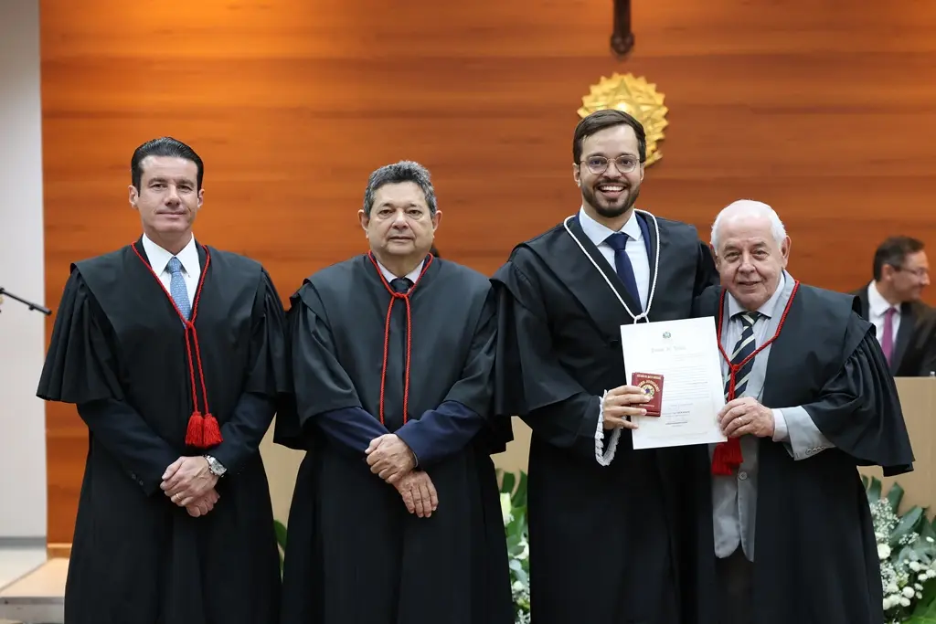 foto horizontal que mostra o juiz Iorran Damasceno ao lado do presidente, do corregedor-geral e do ouvidor do TJMT, durante sua posse como juiz. Todos usam toga e sorriem para a foto.