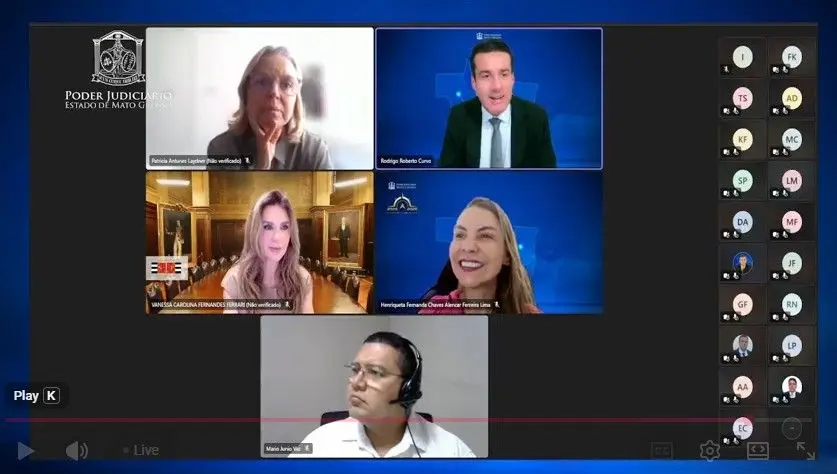 Tela de videoconferência exibe cinco participantes em janelas individuais, cada uma com um fundo diferente, incluindo ambientes internos claros e fundos digitais azuis. À esquerda aparece a marca do Poder Judiciário de Mato Grosso. À direita da tela há uma coluna com diversos ícones representando ou