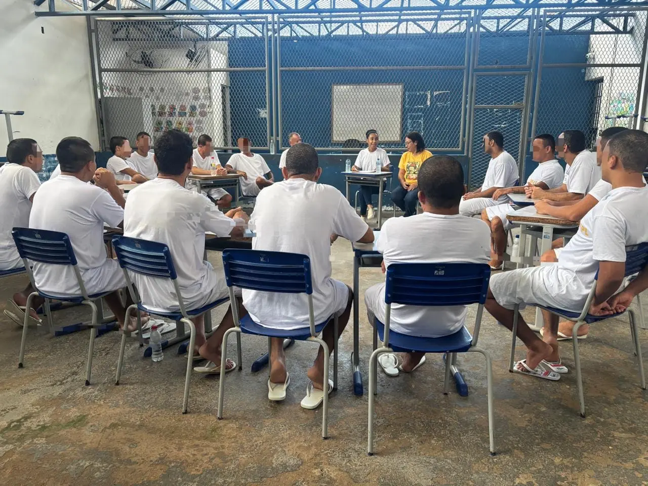 Pessoas privadas de liberdade participam de encontro do Grupo Reflexivo para Homens, realizado no Centro de Detenção Provisória (CDP) de Pontes e Lacerda. Os participantes estão sentados em círculo, em formato de roda de conversa, acompanhados por facilitadoras