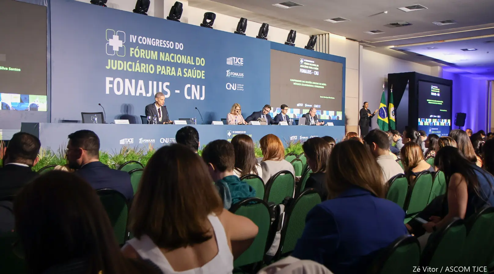 Pessoas assistindo ao IV Congresso do Fórum Nacional do Judiciário para a Saúde (FONAJUS - CNJ), com palestrantes na mesa