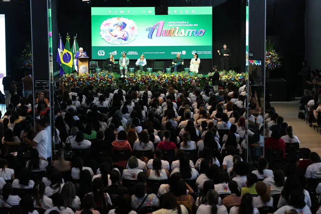 foto em plano aberto que mostra a Igreja Lagoinha lotada de pessoas sentadas, participando do evento TJMT Inclusivo, No placo, há um grande telão com a logomarca do evento.