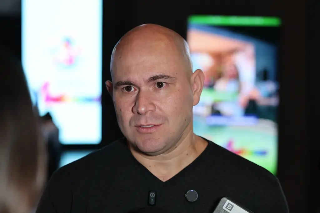 Prefeito Abilio Brunini durante entrevista. Ele é um homem branco, careca, de olhos escuros, usando camiseta preta.