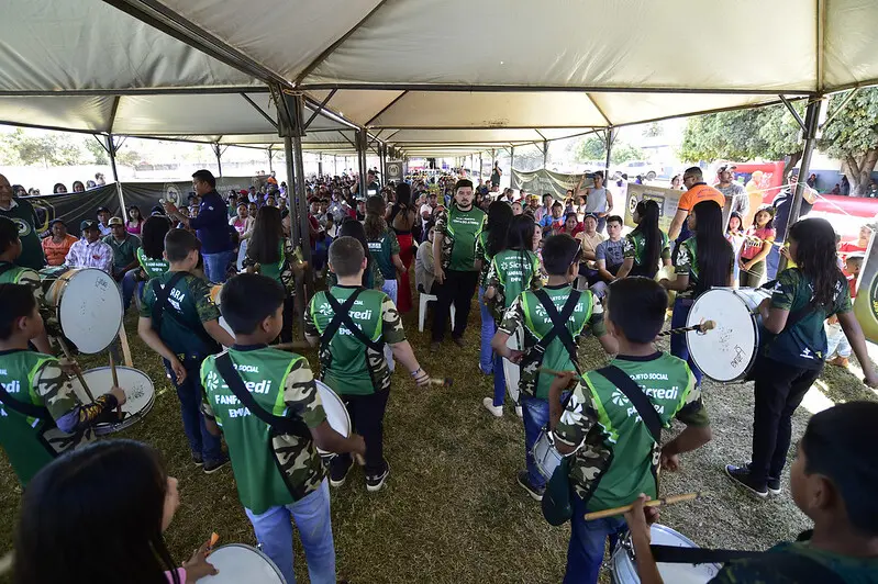 Foto que mostra a fanfarra de alunos da Escola Municipal Ponta do Aterro tocando numa tenda onde ocorreu a expedição Justiça Sem Fronteiras.