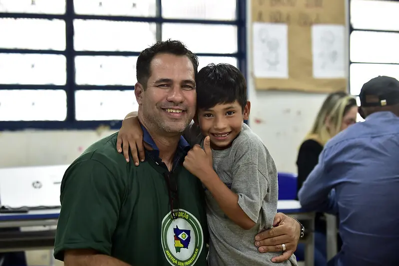 Coordenador da Escola Municipal Ponta do Aterro posa para a foto abraçado com um aluno, Gabriel, de 9 anos. Eles sorriem e Gabriel faz sinal de joia com a mão.