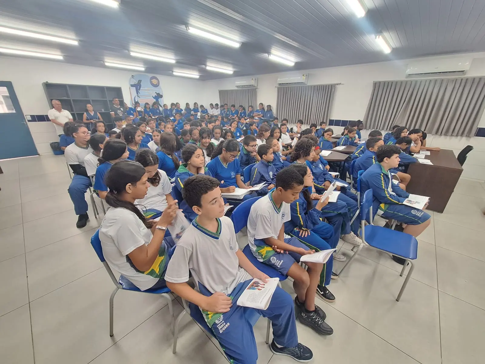 Foto horizontal que mostra dezenas de estudantes em uma sala de aula, sentados assistindo palestra do projeto Nosso Judiciário.