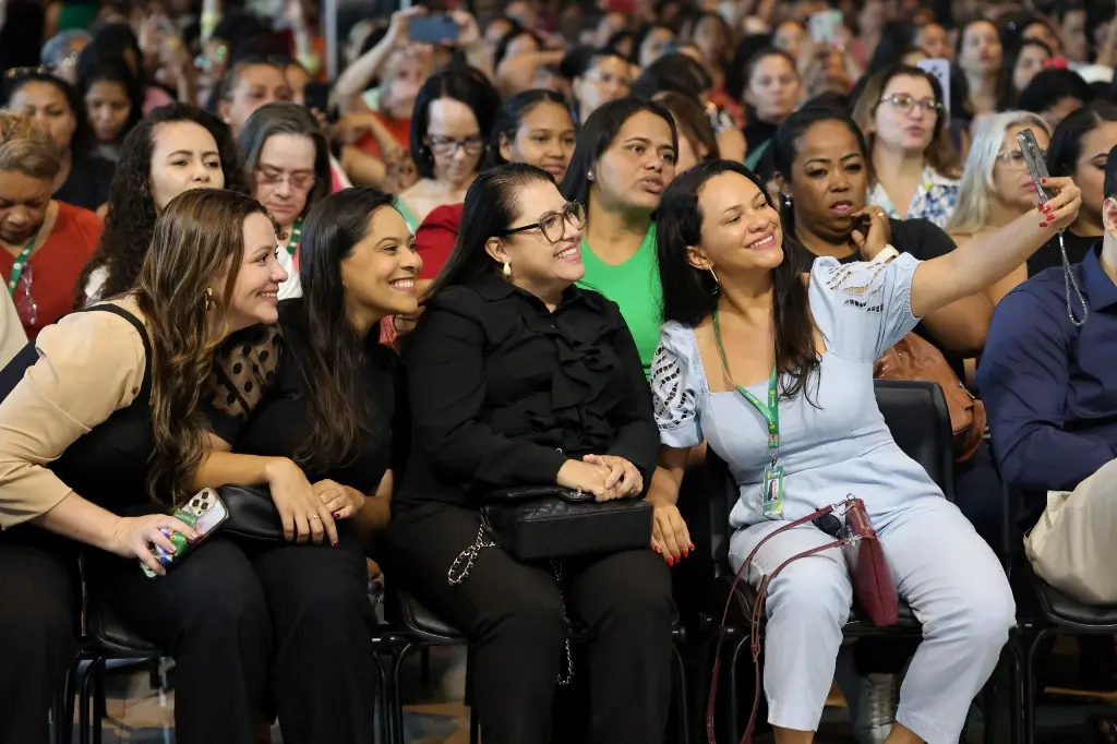 Foto horizontal colorida que mostra o público do evento TJMT Inclusivo sentado em cadeiras. Em primeiro plano, aparece um grupo de quatro mulheres tirando uma selfie, sorrindo.