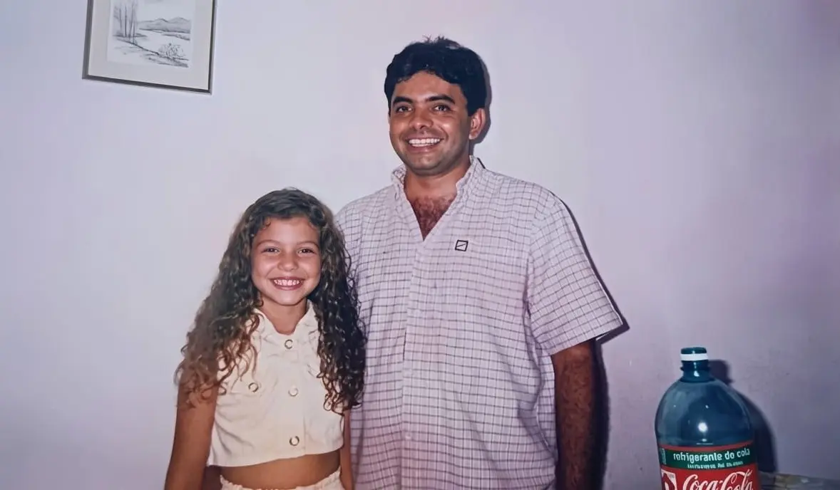 Foto horizontal dos anos 1990 que mostra o agente da Infância e Juventude Aparecido Donizete abraçado com a filha Érica, que tinha cerca de 10 anos na foto. Ela era uma menina de pele clara com longos cabelos loiros e cacheados.