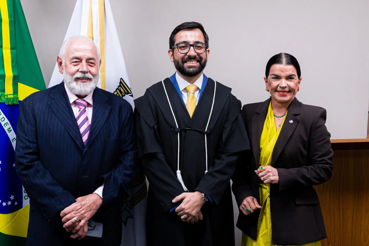 Foto horizontal que mostra, da esquerda para a direita, o presidente do TJMT, desembargador José Zuquim Nogueira, o juiz empossado Eduardo Henrique Minosso e a presidente da Associação Mato-grossende de Magistrados, juíza Jaqueline Cherulli, posando para a foto, sorrindo.