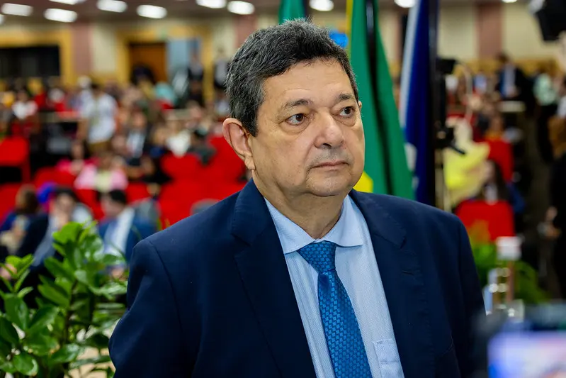 Foto horizontal colorida, em plano médio, que mostra o desembargador e corregedor-geral da Justiça, José Lindote, em pé. Ele é um senhor de pele clara, cabelos grisalhos, olhos castanhos, usando camisa gravata e terno em diferentes tons de azul, do mais claro ao mais escuro. 