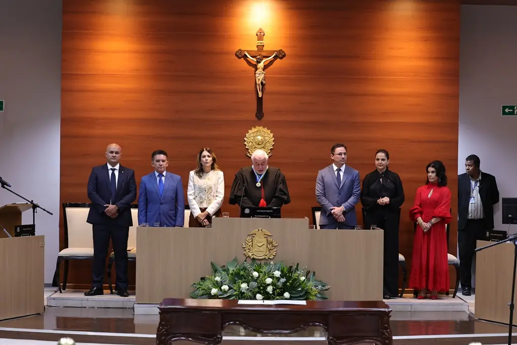 Foto horizontal em plano aberto que mostra o dispositivo de honra da sessão solene de posse, composta por autoridades, no Plenário 1 do Tribunal de Justiça. 
