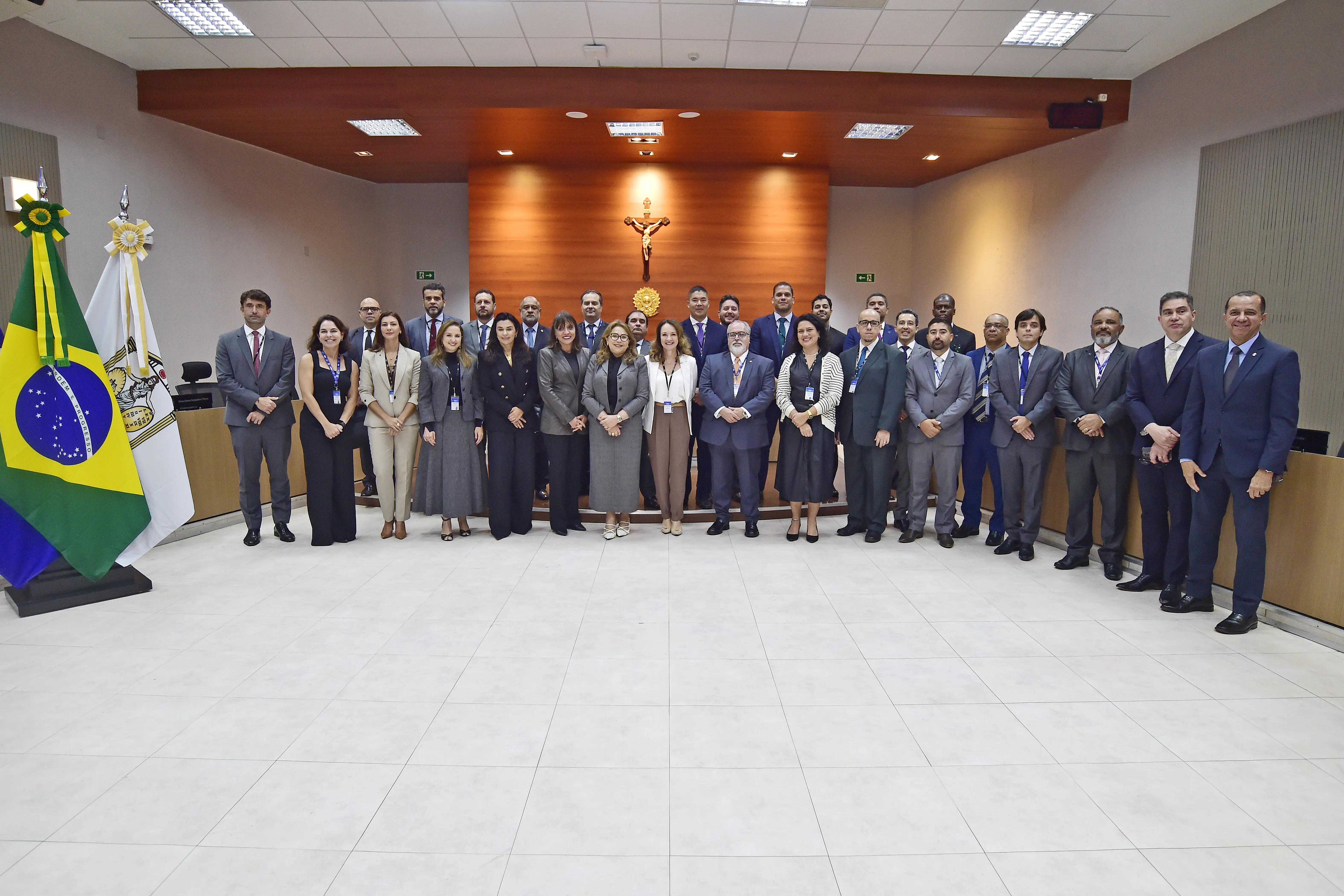 Foto em plano aberto que mostra a equipe de inspeção do CNJ posando para a foto, no centro do Plenário 1 do TJMT. Há 30 pessoas na foto, em pé e sorrindo. 