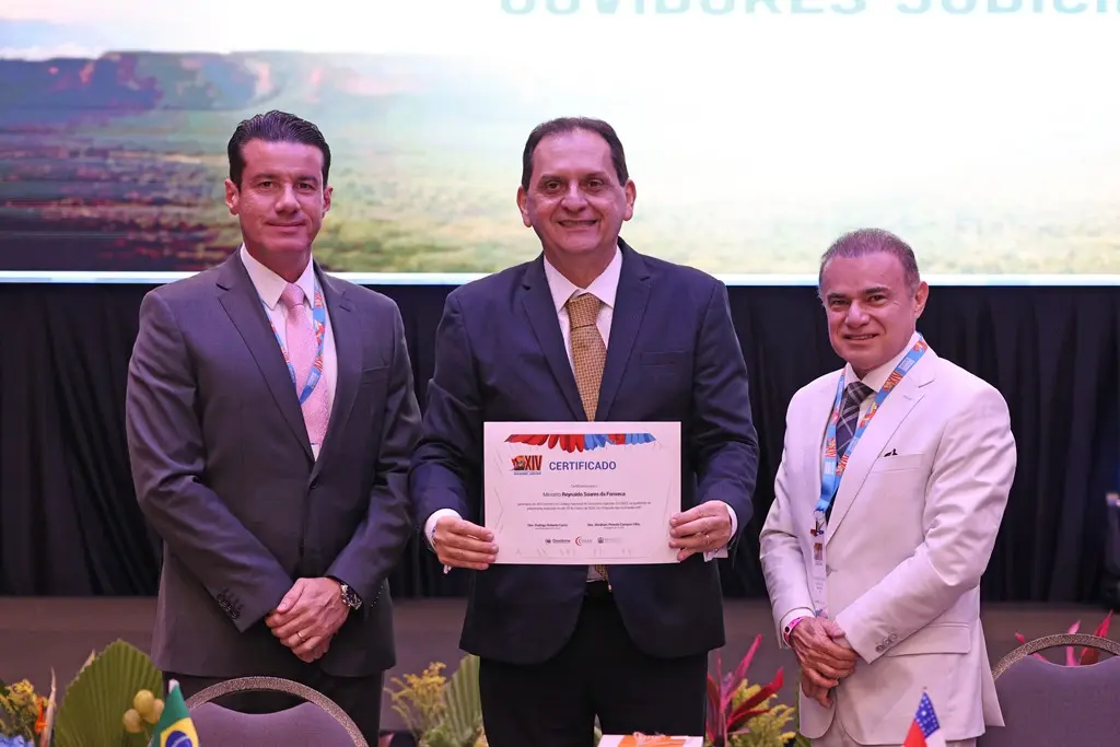 Foto horizontal em plano médio que mostra o ministro ouvidor do STJ, Reynaldo Soares da Fonseca, ladeado pelo presidente e pelo vice-presidente do Colégio Nacional de Ouvidores Judiciais. O ministro exibe o certificado de participação no 14º Encontro do Cojud.
