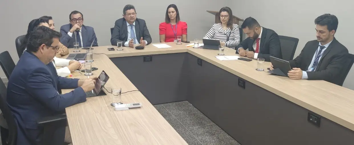 A mesa de reunião em formato de U, com o corregedor ao centro e os demais participantes ao lado.