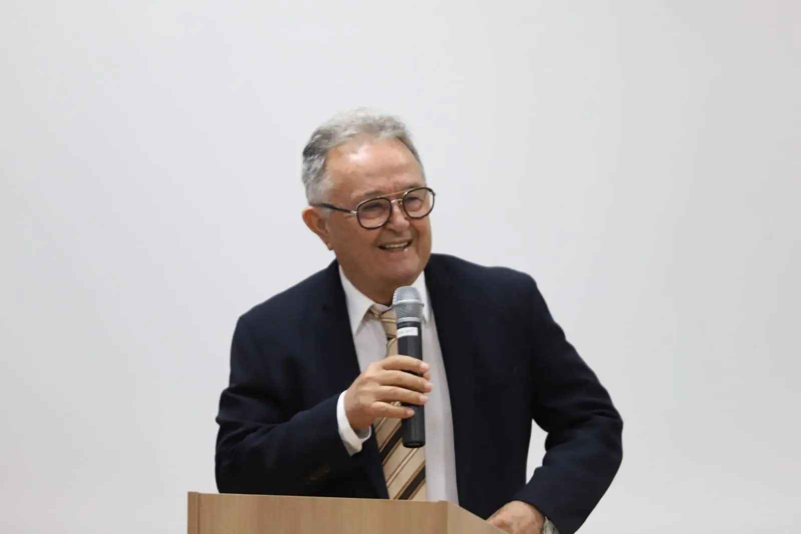 Desembargador Guiomar Teodoro Borges fala aos presentes. Ele é um homem branco, usa terno azul escuro, camisa branca, gravata beje listrada com marrom. Usa óculos de grau e tem cabelos grisalhos