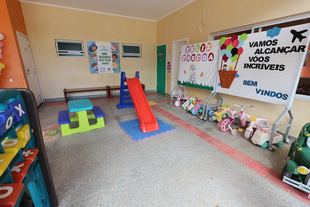 Foto horizontal colorida que mostra o pátio da creche Nina Zaque repleto de brinquedos como escorregador, bicicletas, motoquinhas.