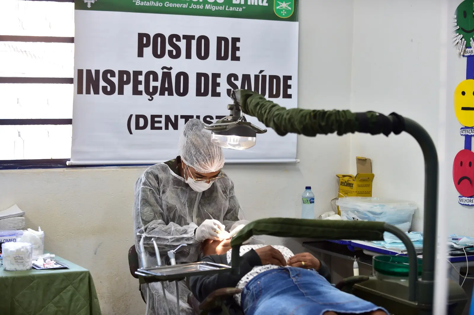 Foto da dentista do Exército realizando procedimento na boca de um paciente.