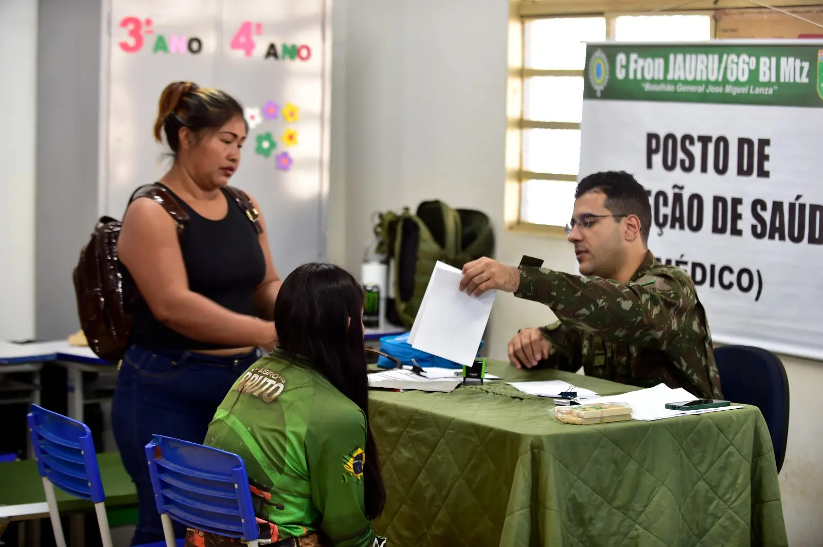Médico do Exército durante atendimento a uma paciente adolescente. A mãe dela está ao lado da filha, em pé.