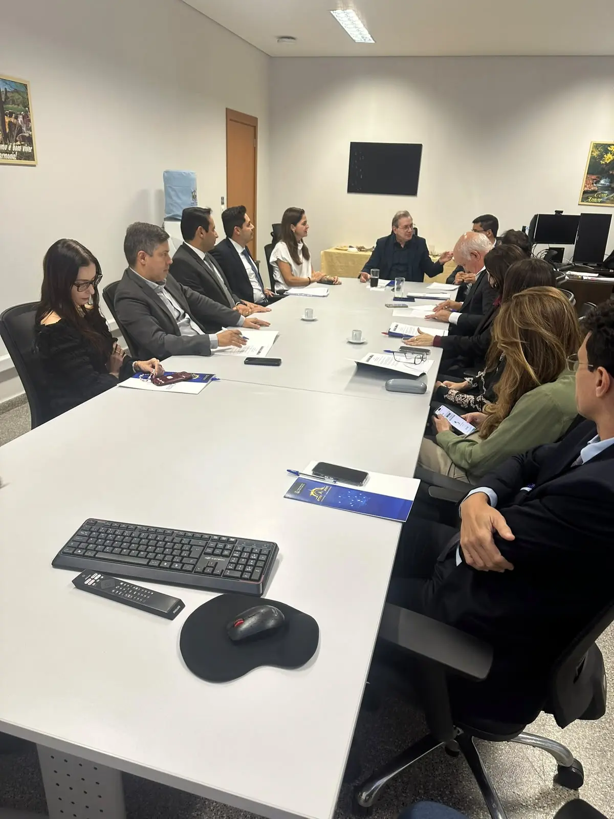 Foto vertical que mostra diversas pessoas sentadas em volta de uma mesa retangular, durante reunião do Conselho de Supervisão dos Juizados com representantes da OAB-MT.
