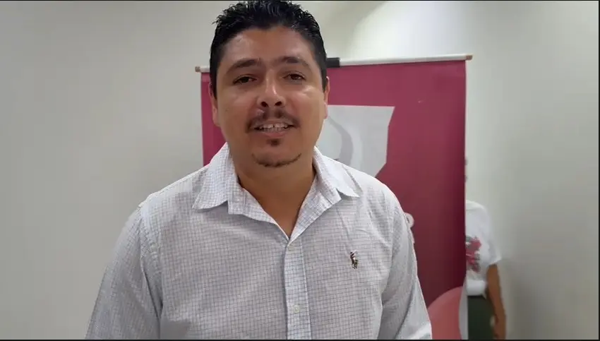 Vice-prefeito de Nortelândia, Rubilan de Oliveira aparece de frente, em ambiente interno claro, vestindo camisa social clara. Ele tem barba fina, cabelos escuros e sorri levemente. Ao fundo, vê-se um banner rosa do CEMULHER, indicando evento institucional no local.