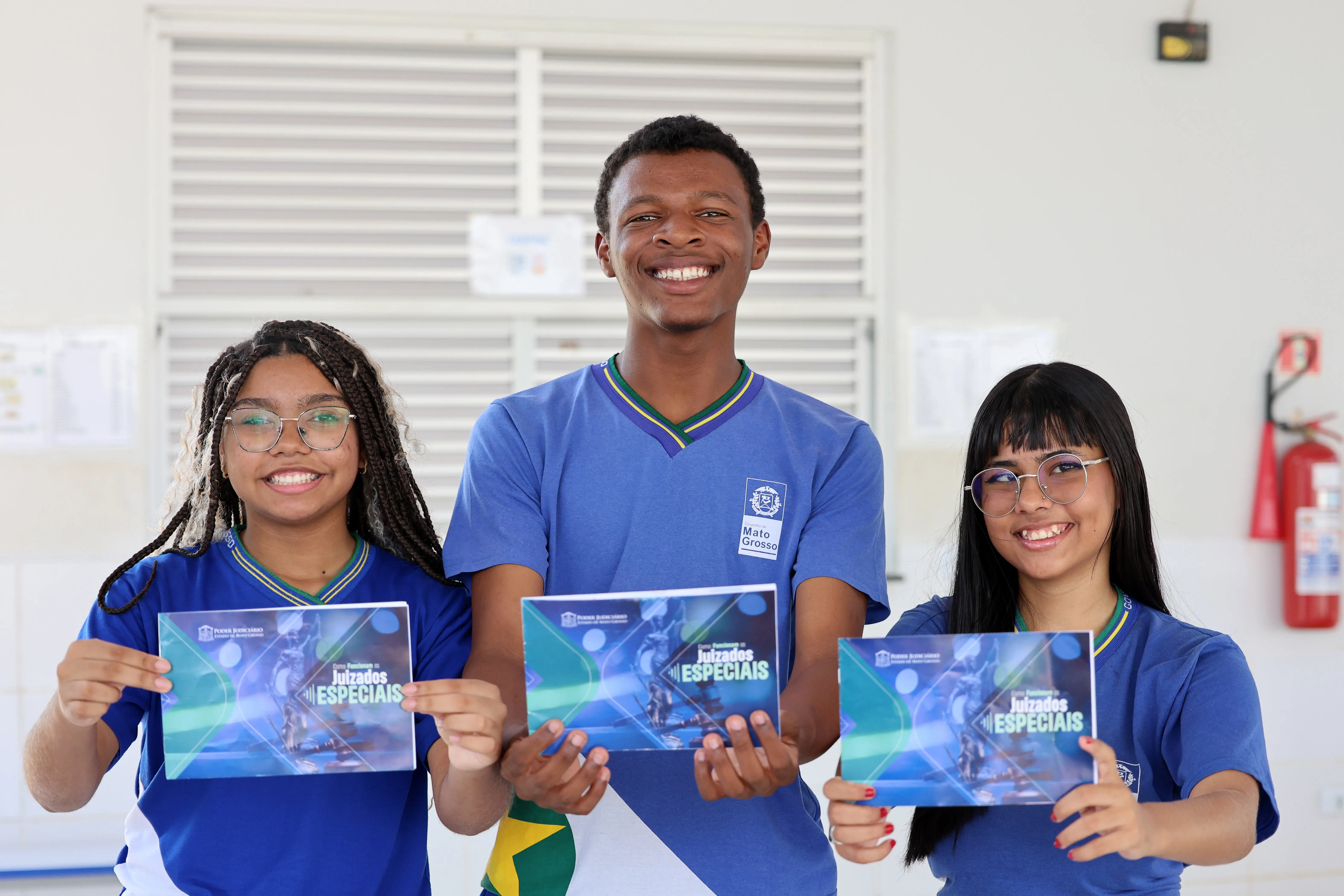 Alunos da Escola Estadual Hélio Palma de Arruda posam para a foto sorrindo e segurando a cartilha do projeto Nosso Judiciário.