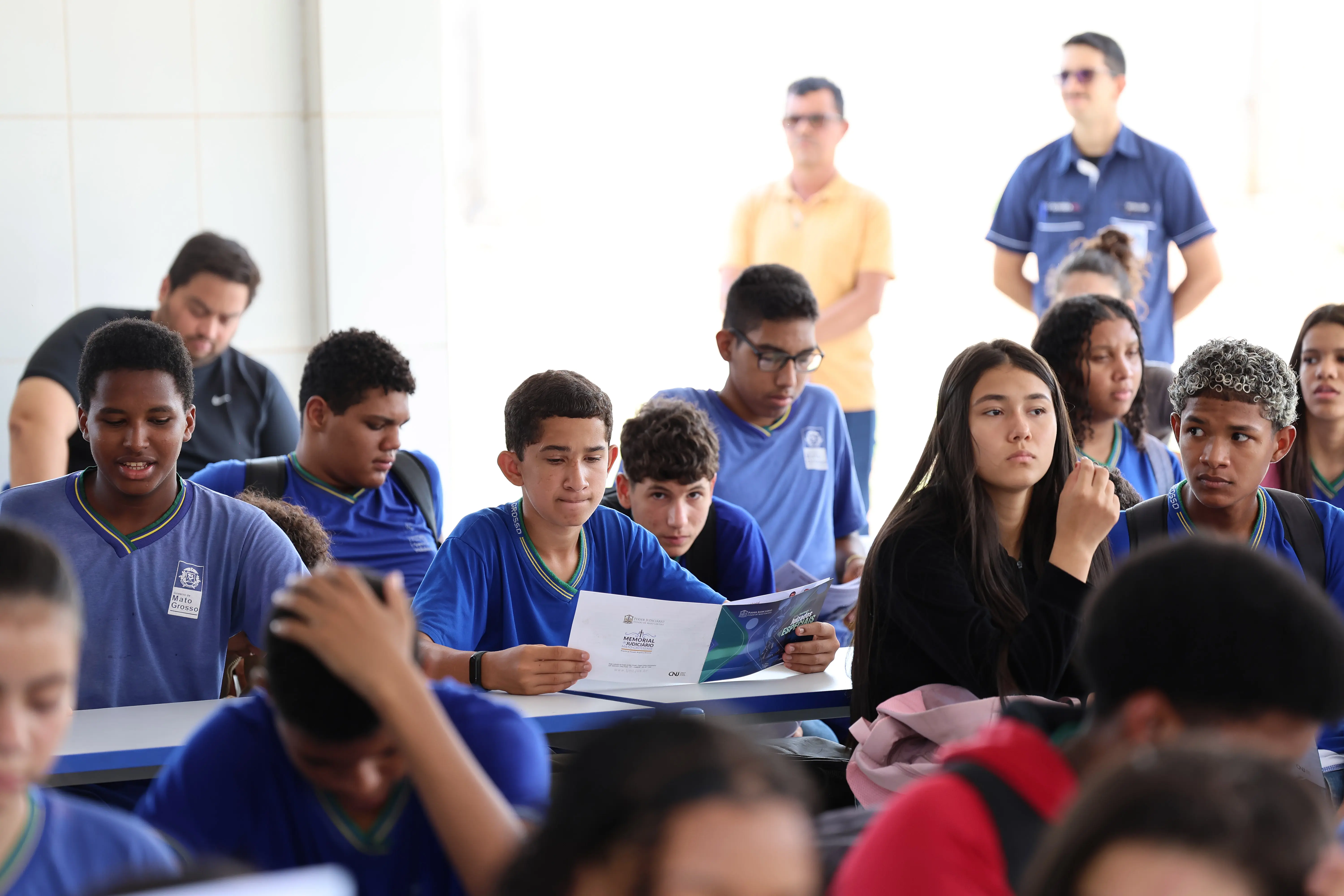 foto em plano aberto que mostra dezenas de estudantes com uniforme azul da Escola Estadual sentados, participando da palestra do projeto Nosso Judiciário.