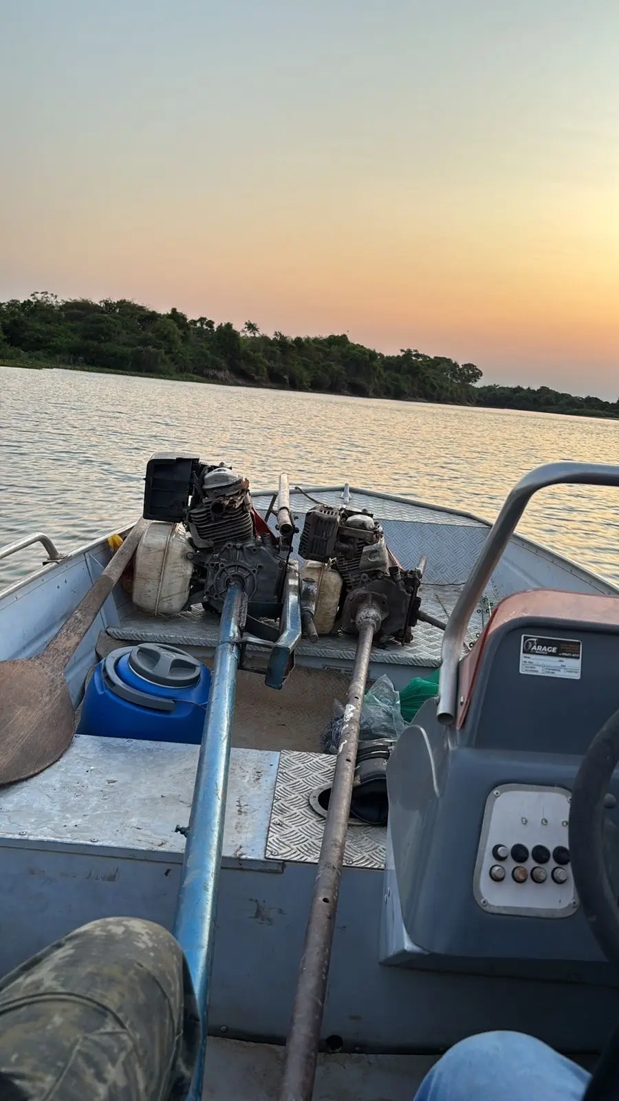 Barco metlico navega por rio cercado de mata sob o pr do sol. No interior, motores de rabeta apreendidos, remos e equipamentos de fiscalizao ambiental utilizados durante operao do Juvam em Cceres.
