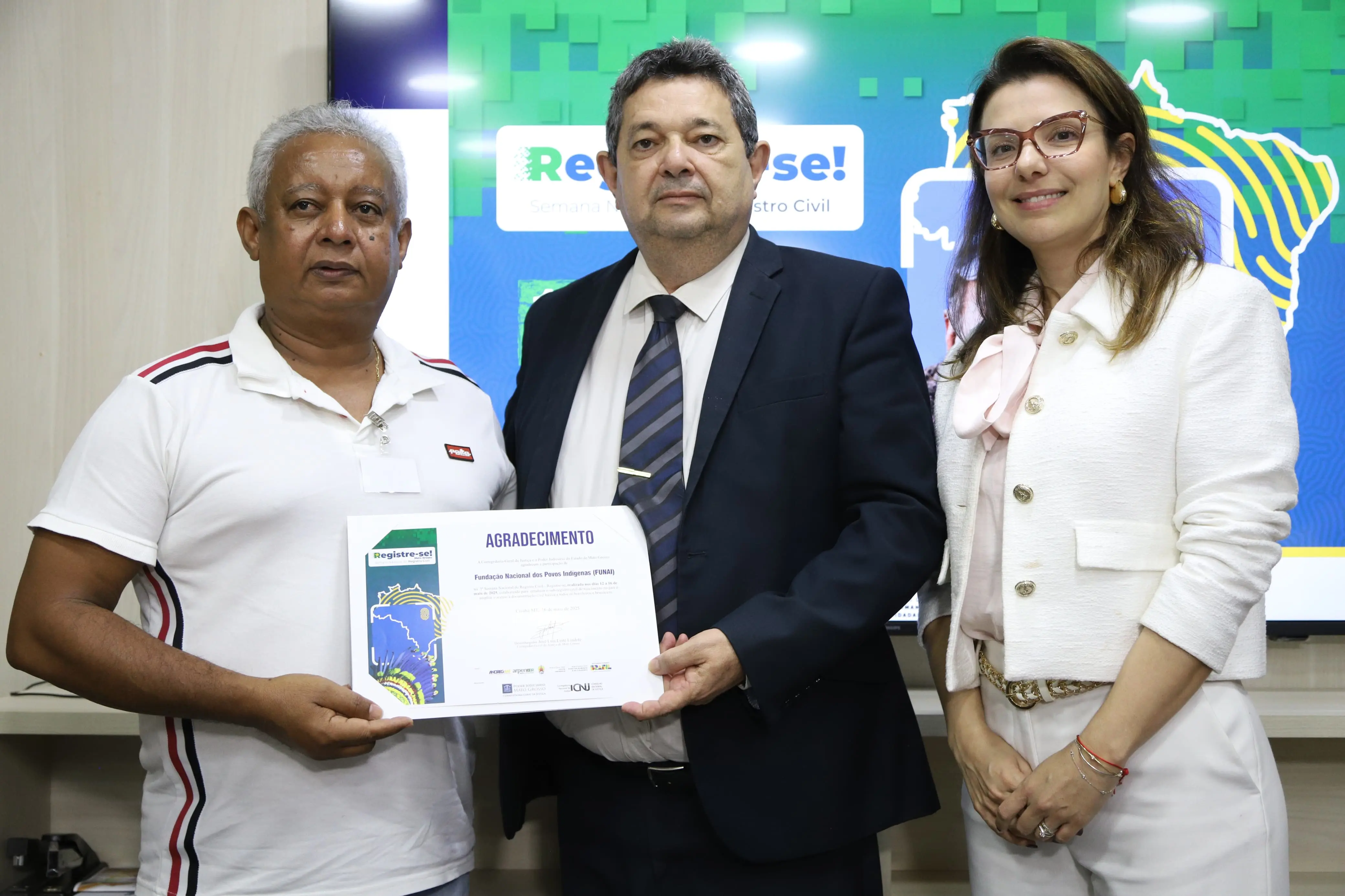 O corregedor, desembargador José Luiz Leite Lindote e a juíza auxiliar Myrian Pavan Schenkel entregam o certificado ao chefe do serviço de promoção dos direitos sociais e de cidadania indígena da Funai Cuiabá, Sebastião de Jesus.