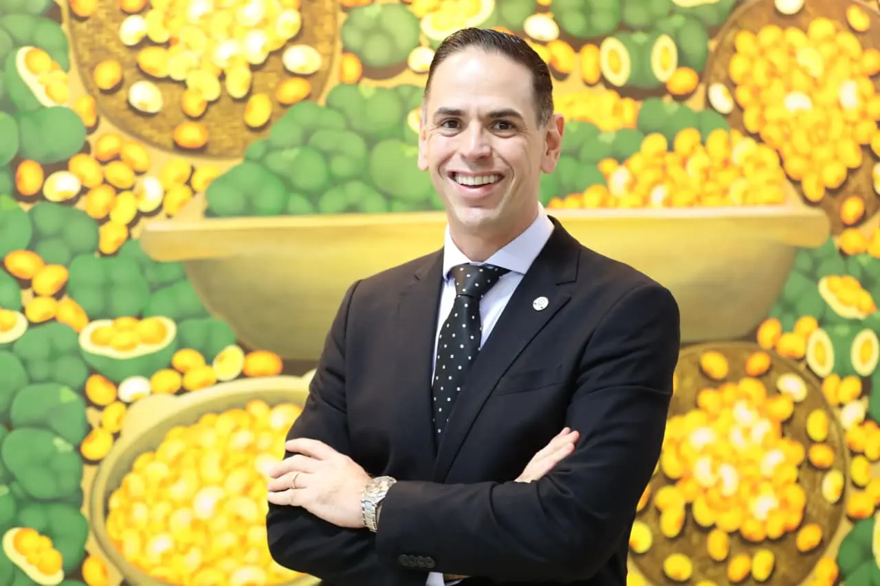 Carlos Eduardo Silva e Souza é um homem branco, de cabelos curtos e está sorrindo. Ele veste terno preto, camisa branca e gravata preta