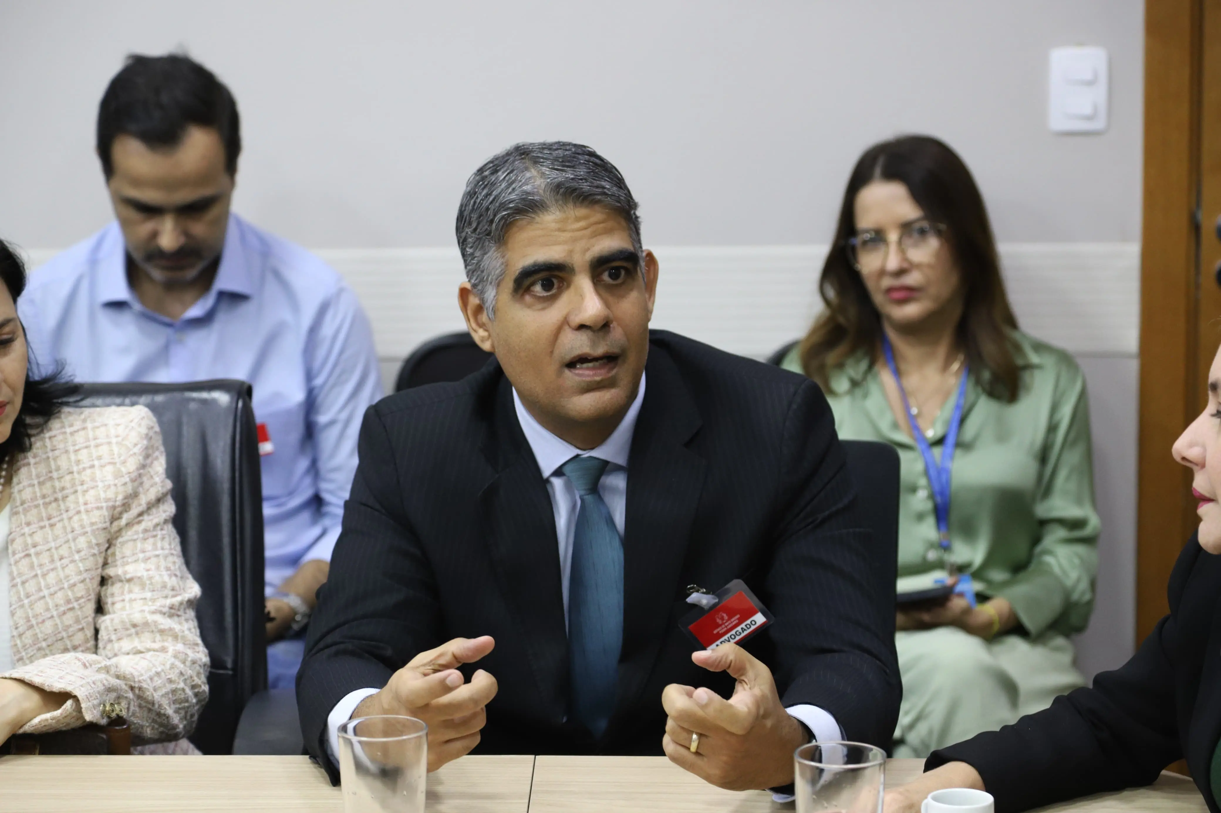 O presidente da Arpen, Rodrigo Oliveira Castro, fala com os presentes. Ele é um homem pardo, de cabelos grisalhos, está usando um terno preto com riscas em branco, camisa e gravata azul