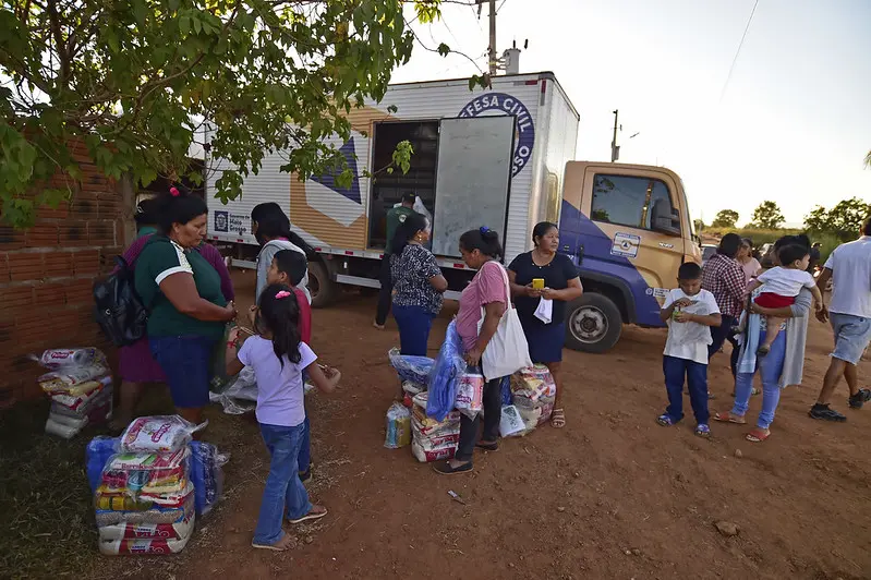 Várias pessoas recebem sacolões em um caminhão da Defesa Civil.