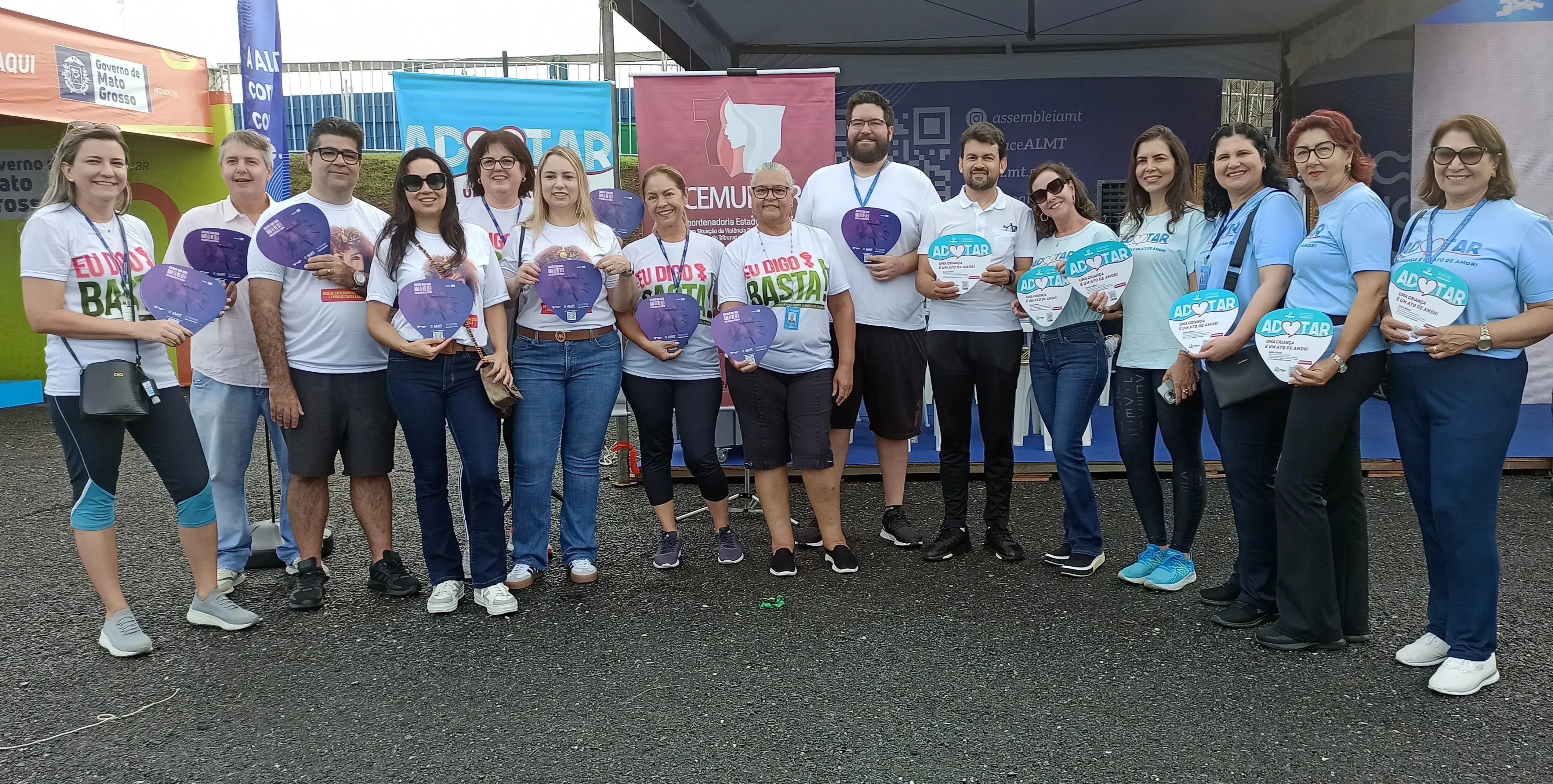 Grupo de servidores do PJMT posa para foto durante a Corrida de Reis, segurando materiais informativos sobre adoção