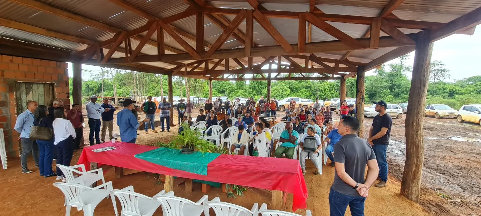Visita técnica Gleba Rio Ferro, em Feliz Natal. O juiz Alex Nunes está de pé e  conversa com moradores, que estão sentados, em uma barracão.