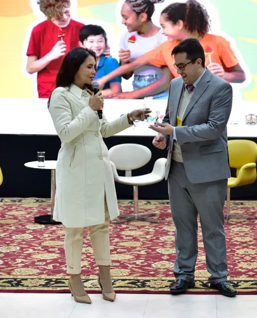 Juíza Anna Paula, usa casaco claro e entrega lembrança a palestrante durante o 4º Encontro Estadual de Defesa dos Direitos da Criança e do Adolescente, em auditório com painel do evento ao fundo