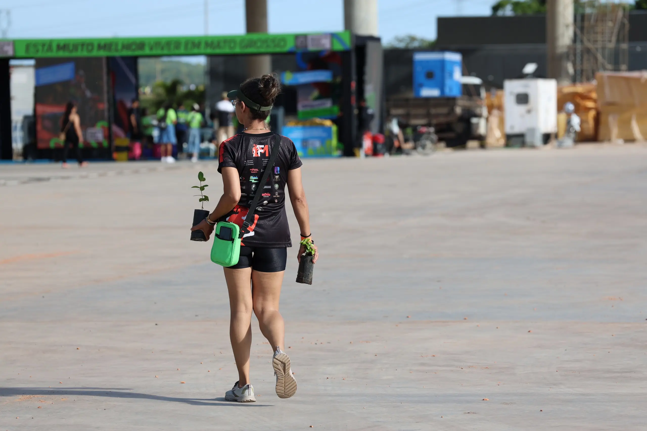 Atleta corre sozinho em área aberta, usando camiseta escura e número de peito. Ao fundo, a pista segue livre, com vegetação e céu aberto ao redor.