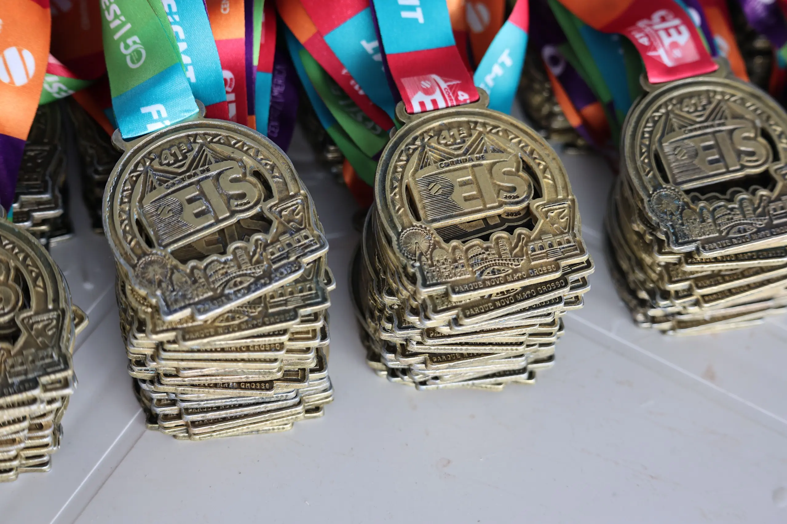 Close de medalhas da corrida dispostas lado a lado, destacando o acabamento e a identidade visual do evento. A imagem foca nos detalhes do prêmio entregue aos atletas.