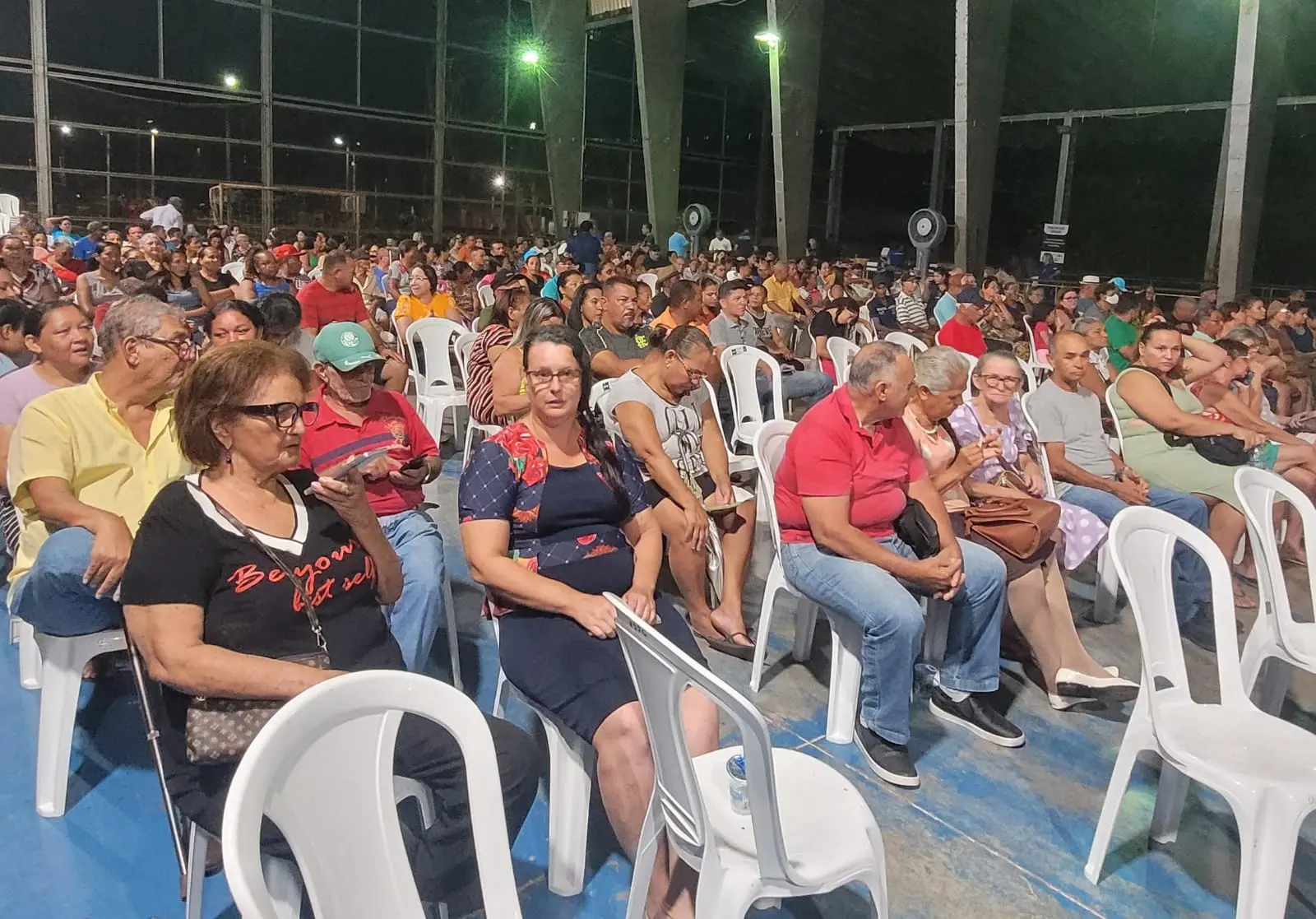 foto horizontal colorida. centenas de pessoas sentadas em cadeiras brancas