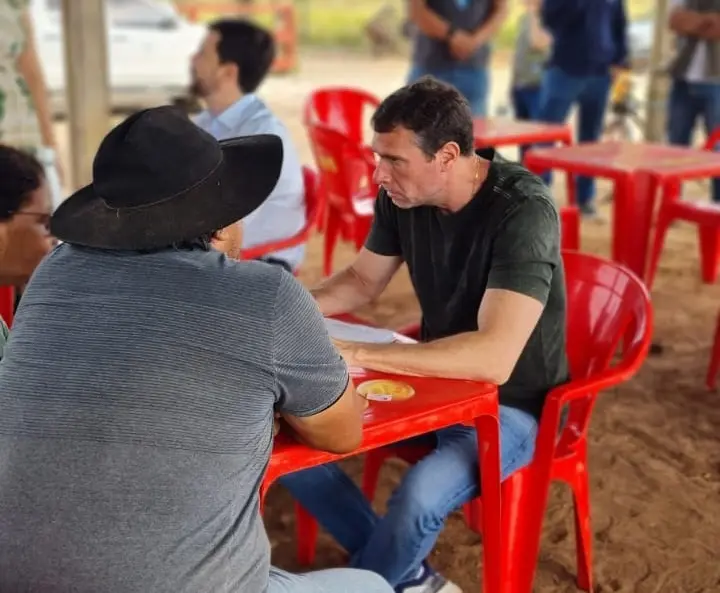O juiz Eduardo Calmon está sentado conversando com moradores e colhendo informações para cadastramento.