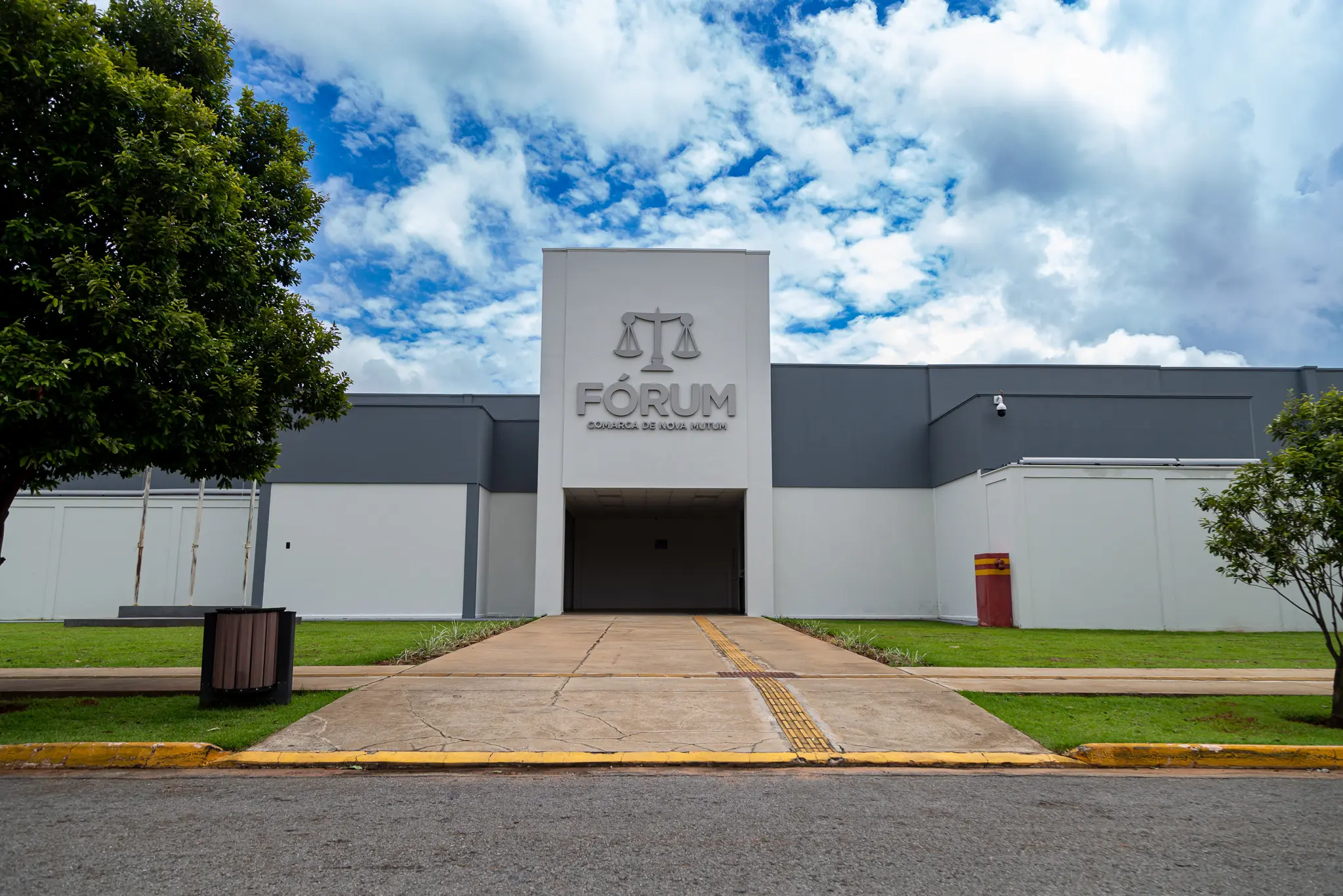 Fachada do Fórum de Nova Mutum é um prédio branco, com detalhes em cinza escuro. Uma rampa leva até a entrada do Fórum