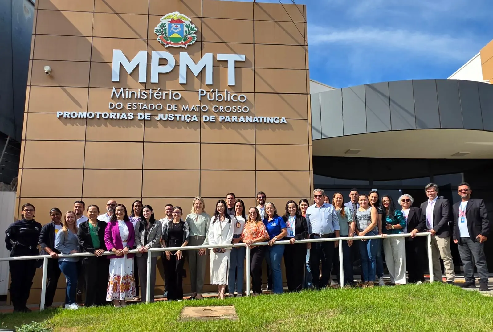 Foto de grupo com cerca de 30 pessoas posando em frente ao prédio do Ministério Público do Estado de Mato Grosso, MPMT. 