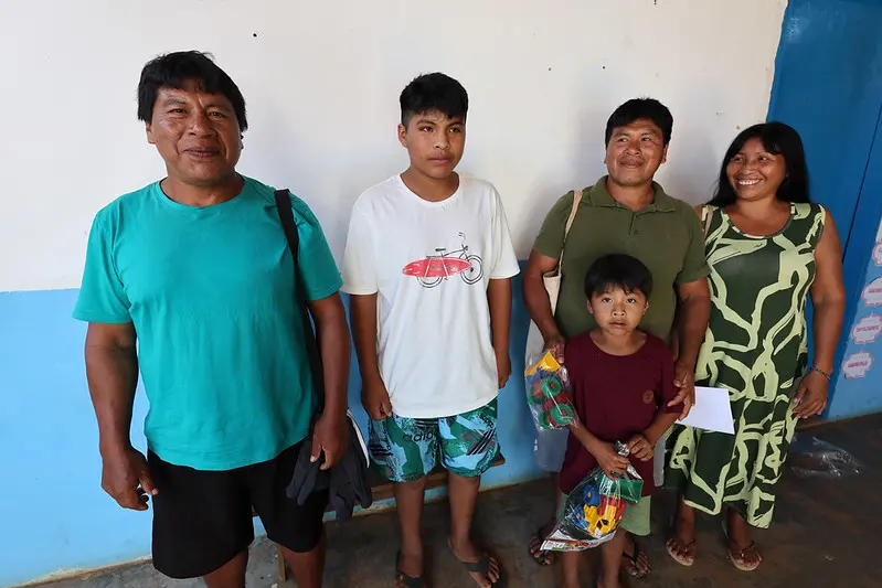 Foto horizontal colorida, em plano aberto, que mostra a família de indígenas Waura, que participou do mutirão Justiça em Ação. Da esquerda para a direita: Tirawa, seu filho, seu irmão, sua cunhada e o sobrinho. Eles estão em pé, posando para a foto.