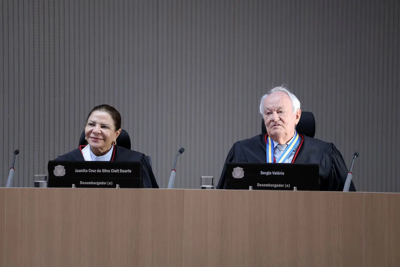 Foto horizontal que mostra a desembargadora Juanita Cruz e o desembargador Sérgio Valerio sentados, no plenário do TJ, lado a lado.