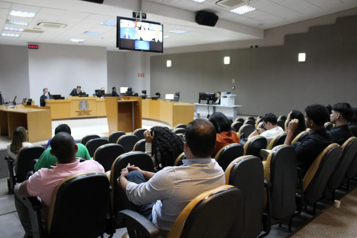Foto horizontal em plano aberto que mostra um plenário do Tribunal de Justiça com a plateia cheia de pessoas assistindo a sessão. Os magistrados estão à frente, sentados à mesa do colegiado.