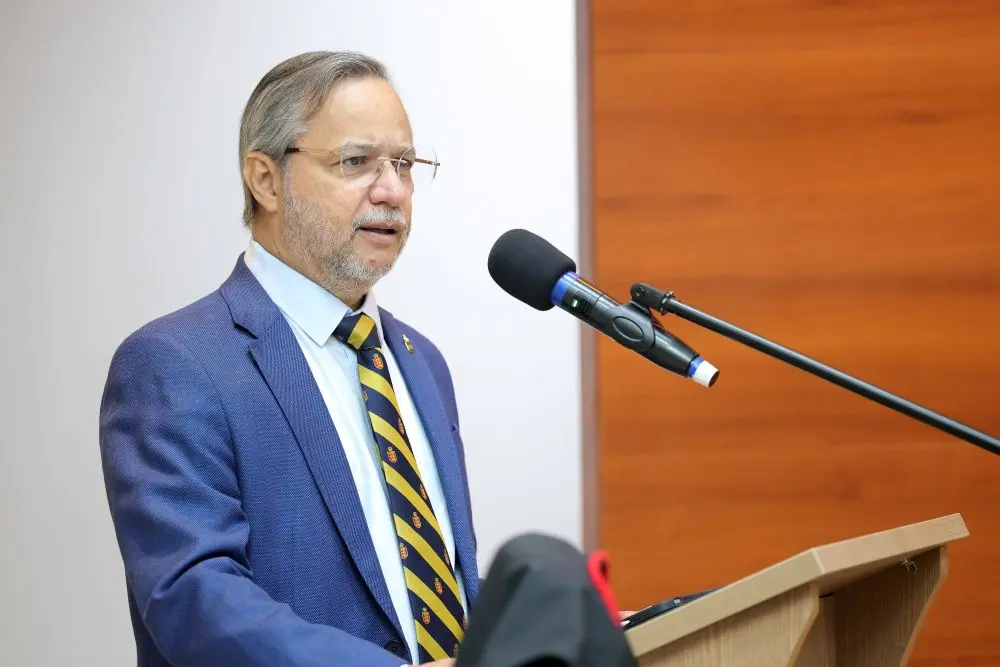 Foto horizontal que mostra o advogado Naim Moraes falando no púlpito do plenário do TJMT. Ele é um homem branco, de cabelo grisalho, usando camisa azul clara, terno azul e gravata listrada azul e amarela.