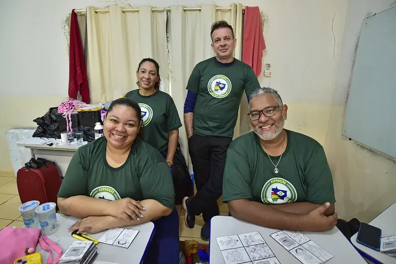 Equipe da Biblioteca Itinerante da Secretaria de Cultura posam sorrindo para a foto. São duas mulheres e dois homens, sendo que dois estão sentados e outros dois em pé.