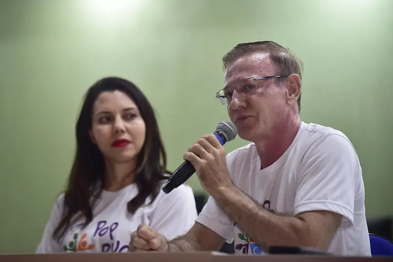 Juiz Wanderlei José dos Reis fala ao microfone. É um homem branco, com cablos castanhos, usa óculos de graui e usa camiseta do mutirão. Ao lado dele está a juíza Aline Quinto, mulher branca, tem cabelos pretos abaixo dos ombros e usa camiseta do mutirão