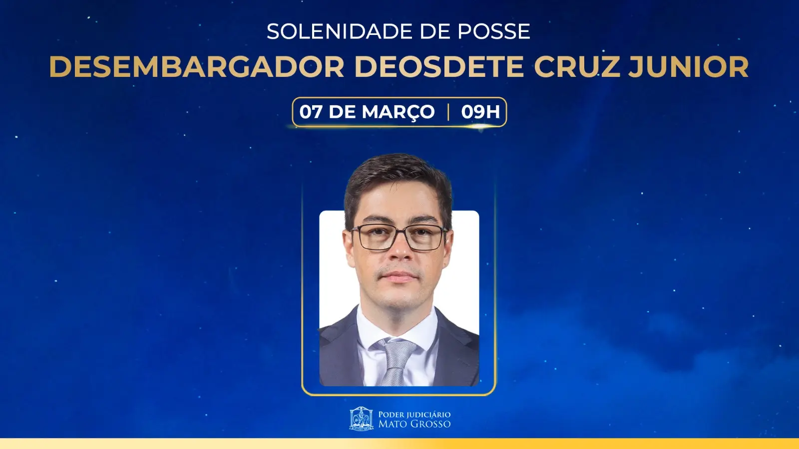 Foto em plano fechado que mostra o promotor de Justiça Deosdete Cruz Júnior. Ele é um homem branco, de olhos e cabelos escuros, usando camisa branca, gravata e terno cinza e óculos de grau de armação preta. Acima da foto está o nome do promotor, data e horário da posse. na base, o logo do PJMT